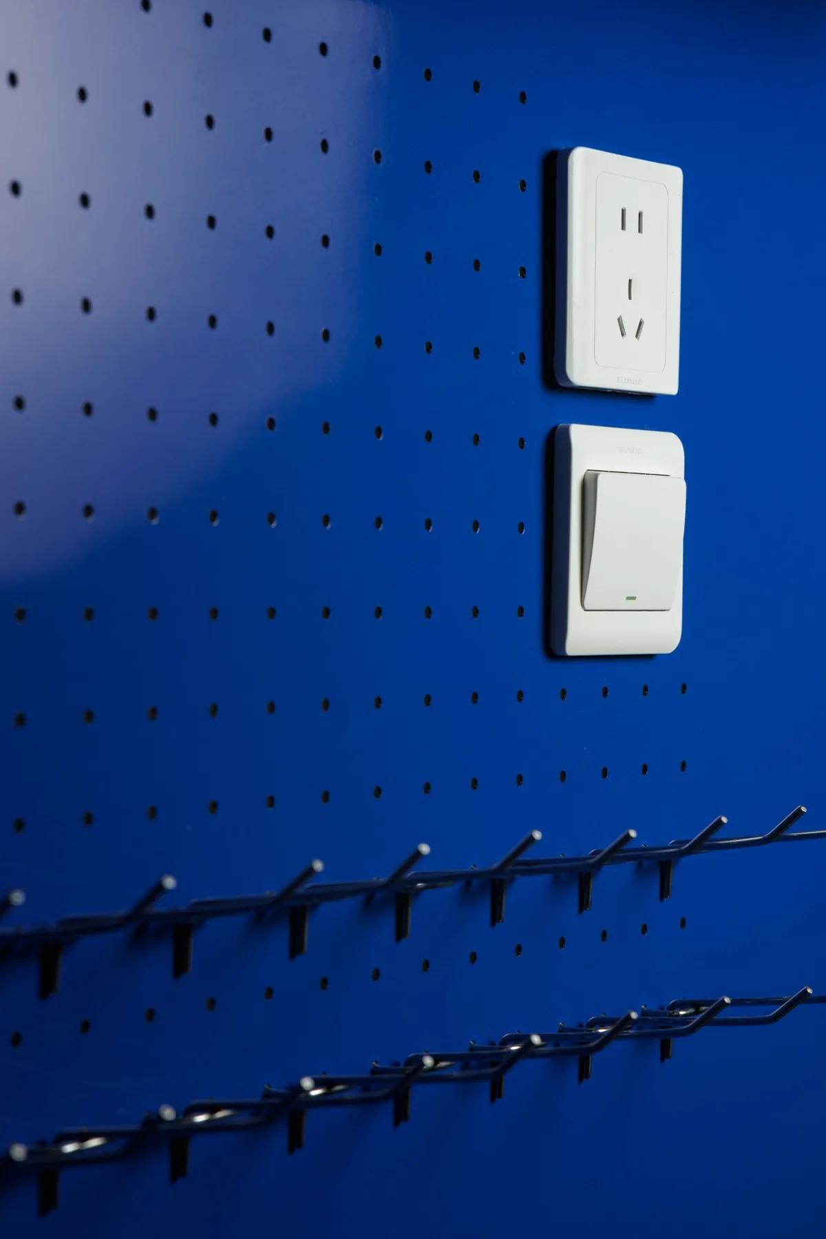 Painel perfurado azul da bancada de trabalho Devoc, com tomada, interruptor e ganchos para ferramentas